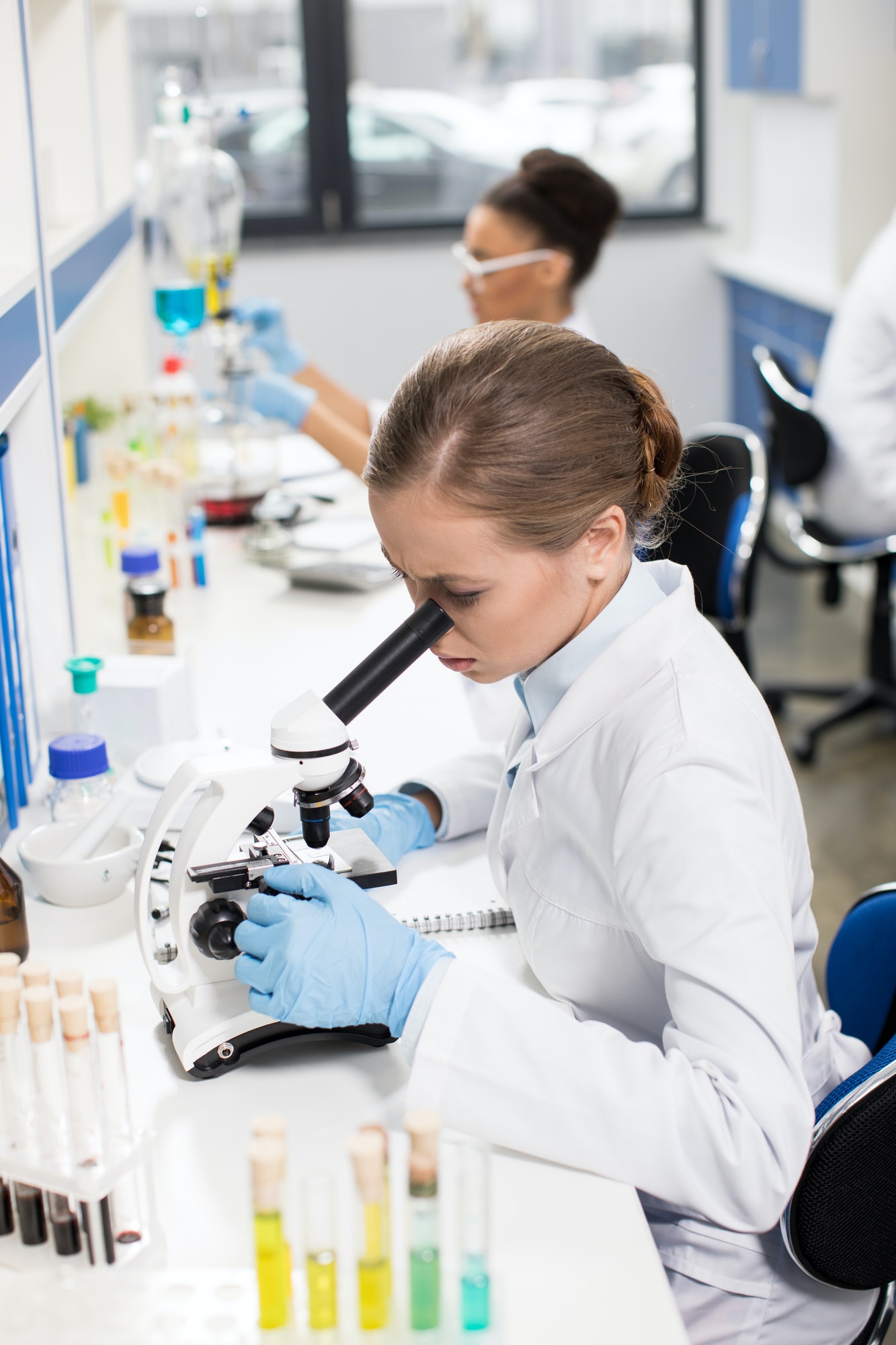 focused-young-scientist-working-with-microscope-in-research-laboratory